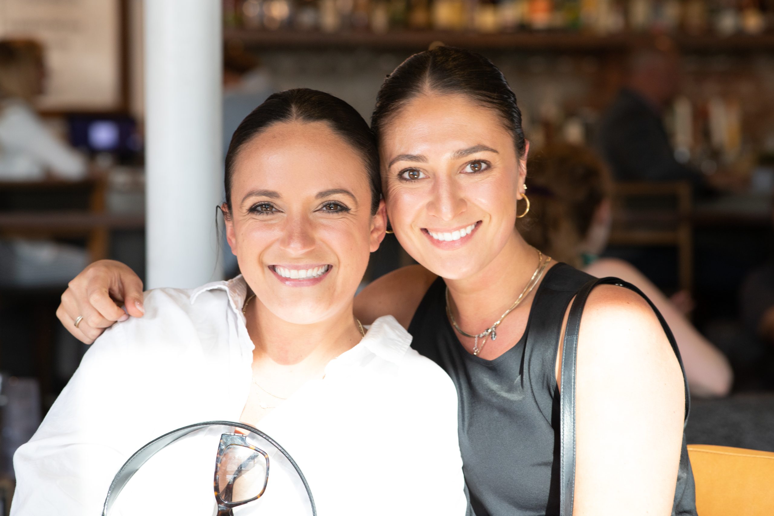 Two women with dark hair smiling together