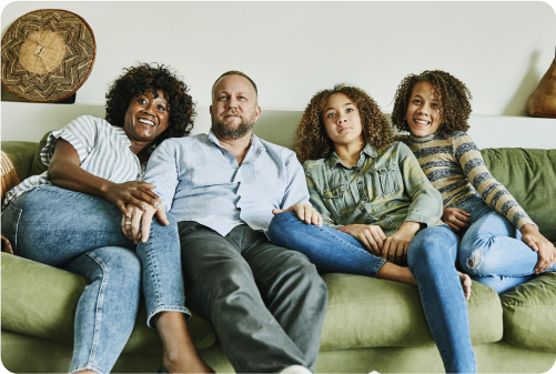 Photo of man, woman and 2 children sitting on couch